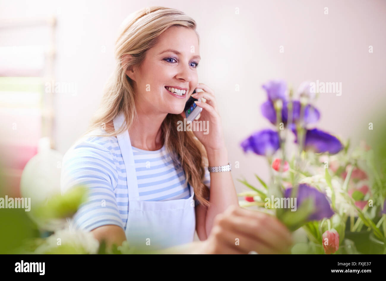 Anordnen von Blumen Blumenladen lächelnd und reden über Handy Stockfoto