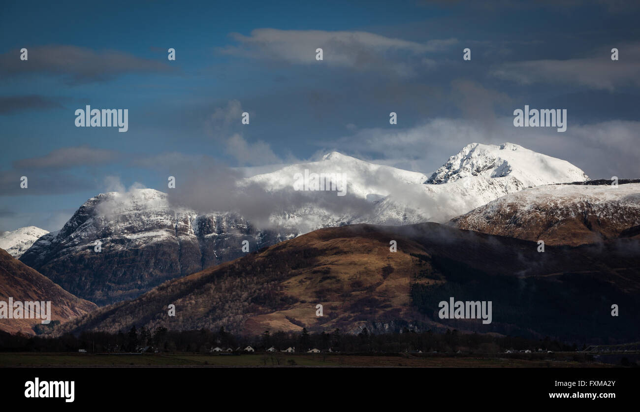 WISPs von niedrigen Wolken vorbei Schnee bedeckt Berge der drei Schwestern von Glencoe und dem Gipfel des Bidean Nam Bian Stockfoto