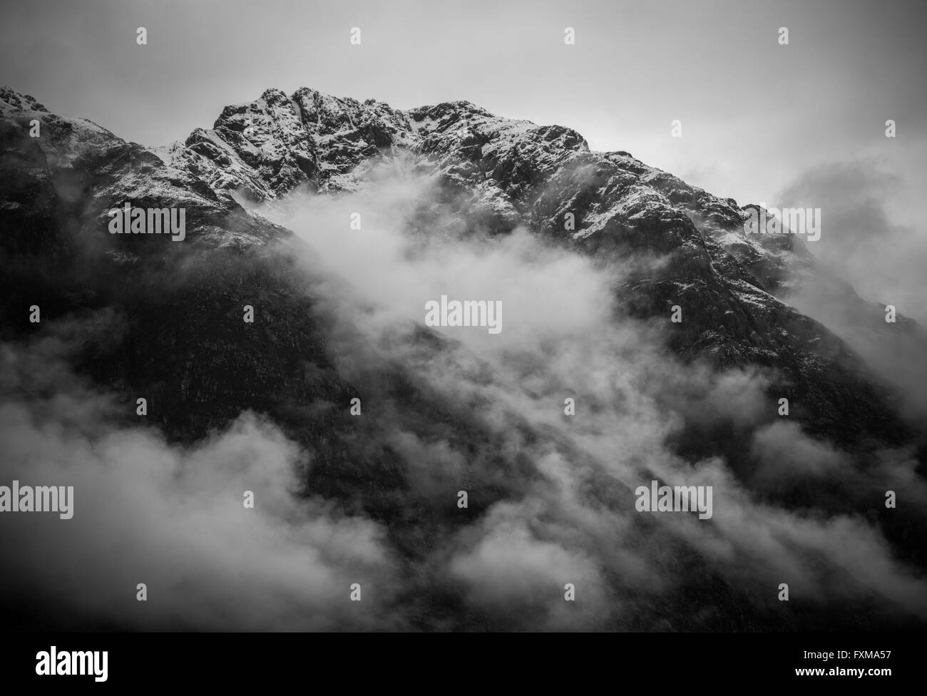 Die Aonach Eagach Ridge Schwelbrand mit niedrigen liegenden Wolken als den exponierten Grat kommt ein-und. Stockfoto