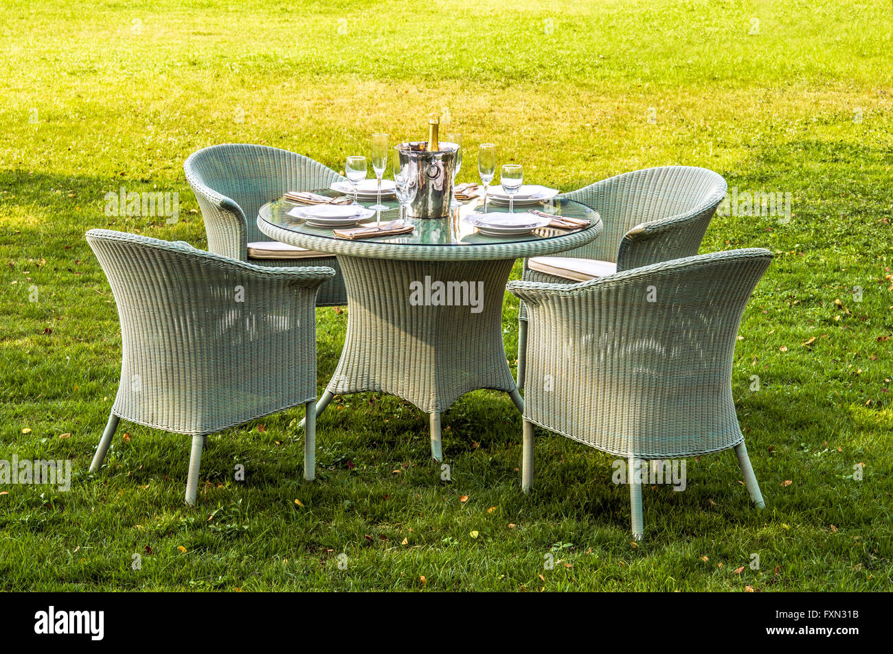 Weiße Rattan-Möbel, Tisch, Stühle und Kissen im Freien im Garten Stockfoto