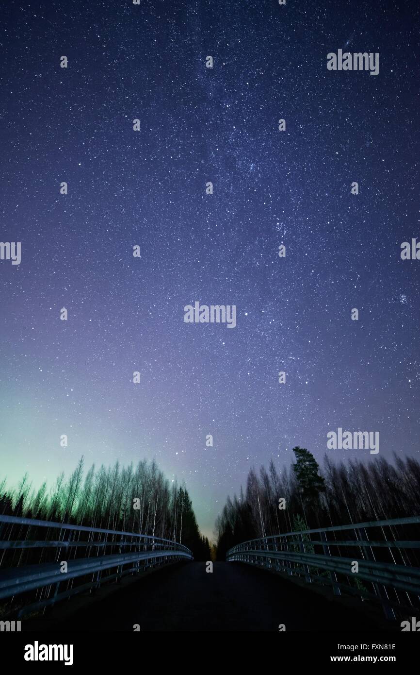 Ein nächtlicher Himmel voller Sterne und sichtbaren Milchstraße mit einer Brücke im Vordergrund. Grünes Licht der Northern Lights auf der linken Seite Stockfoto