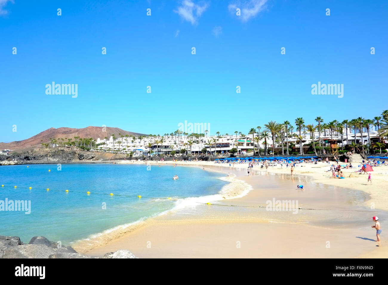 Ein Blick auf den Strand auf der Westseite von Playa Blanca, Lanzarote. Es ist ein warmer Frühlingstag mit Urlauber genießen die Sonne auf einem goldenen Strand Stockfoto