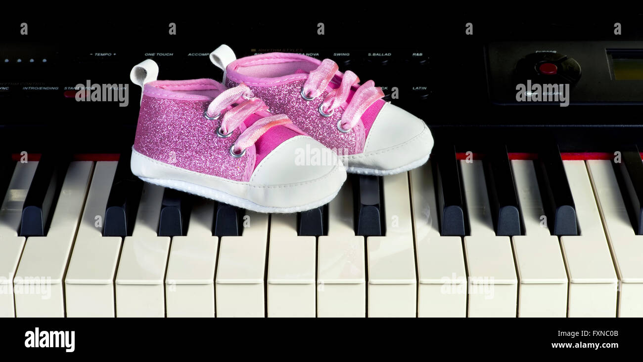 Rosa Babyschuhe auf Klavier Tastatur. Stockfoto