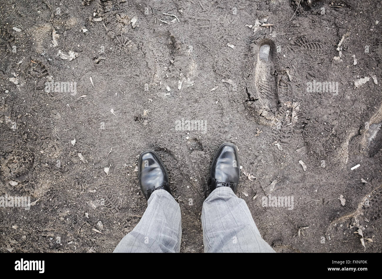 Männliche Füße in neuen schwarz glänzende Lederschuhe auf schmutzige Landstraße, Egoperspektive Stockfoto