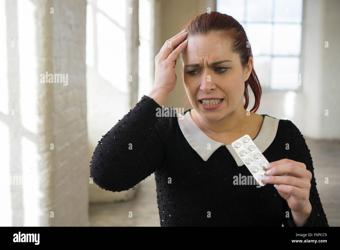 Frau mit Kopfschmerzen hand auf Kopf und Holding Pillen Stockfoto