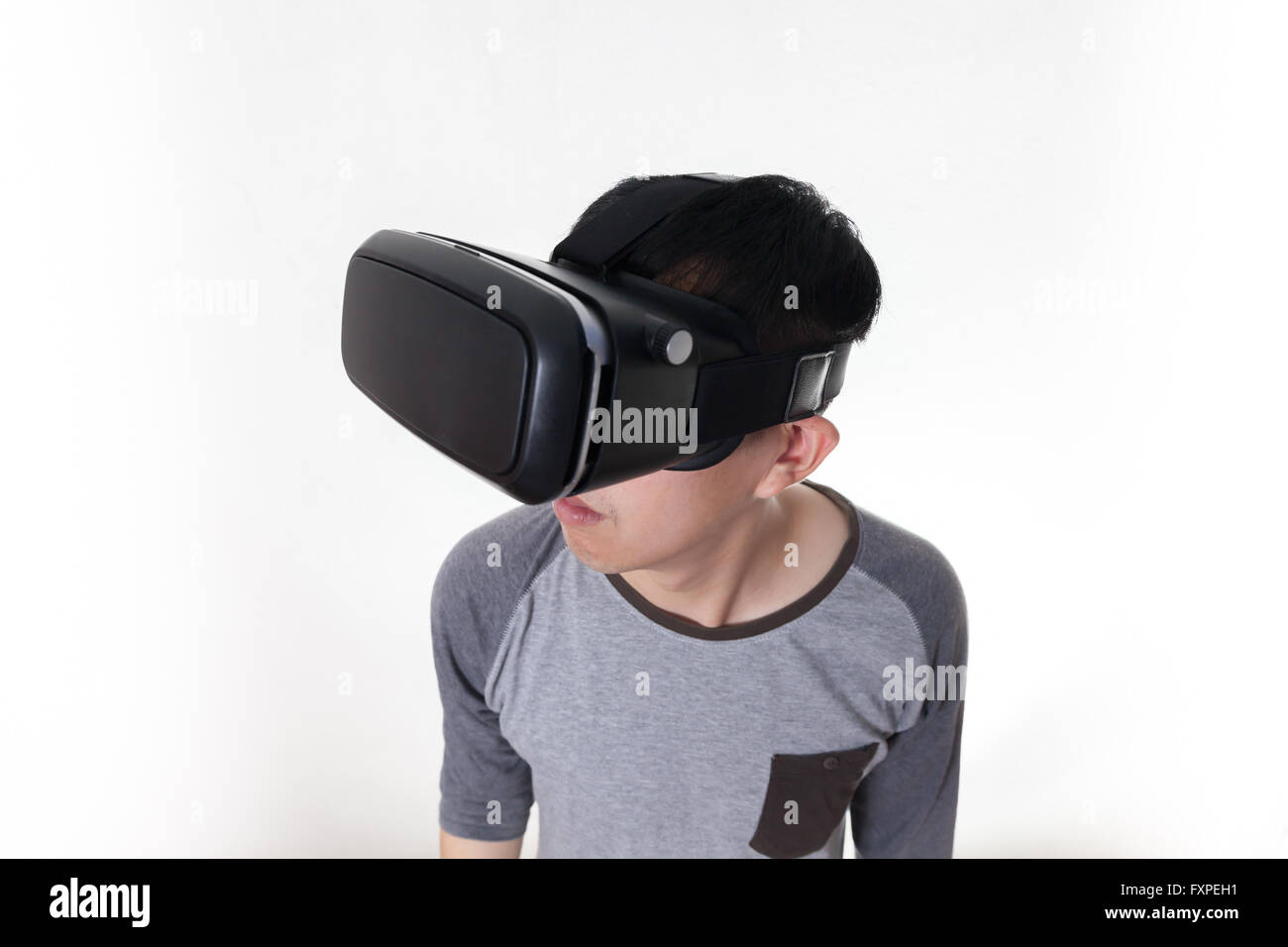 Asiatischer Mann VR Brille tragen und selbst in VR multimedia in weiß isoliert eintauchen. Stockfoto