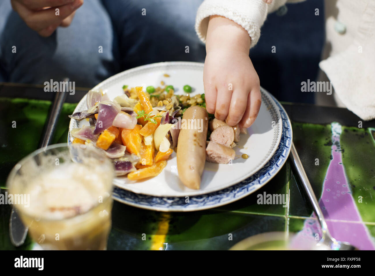 Kleinkind essen Wurst mit Händen Stockfoto
