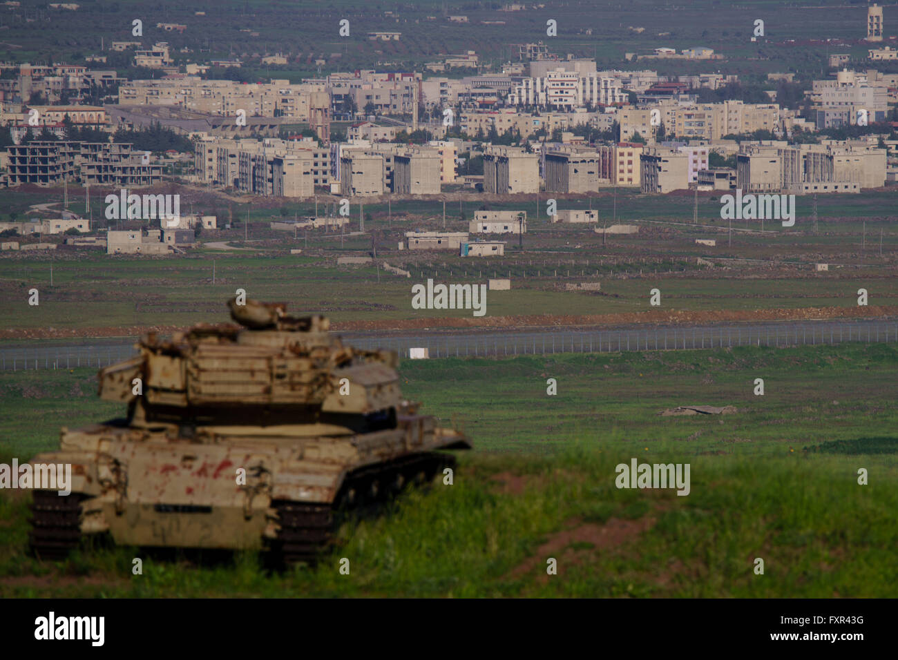 (160417)--JERUSALEM, 17 April (Xinhua)--ein Bild aus dem israelisch besetzten Golanhöhen zeigt Trümmer einer alten Tank vor dem Grenzzaun und Gehäuse in Syriens Quneitra Provinz am 17. April 2016. Der israelische Ministerpräsident Benjamin Netanyahu schwor Sonntag, dass die im Anhang der israelischen Golan-Höhen "forever" unter israelischer Kontrolle in einer ersten Kabinettssitzung auf dem umkämpften Gebiet bleiben. (Xinhua/JINI) Stockfoto
