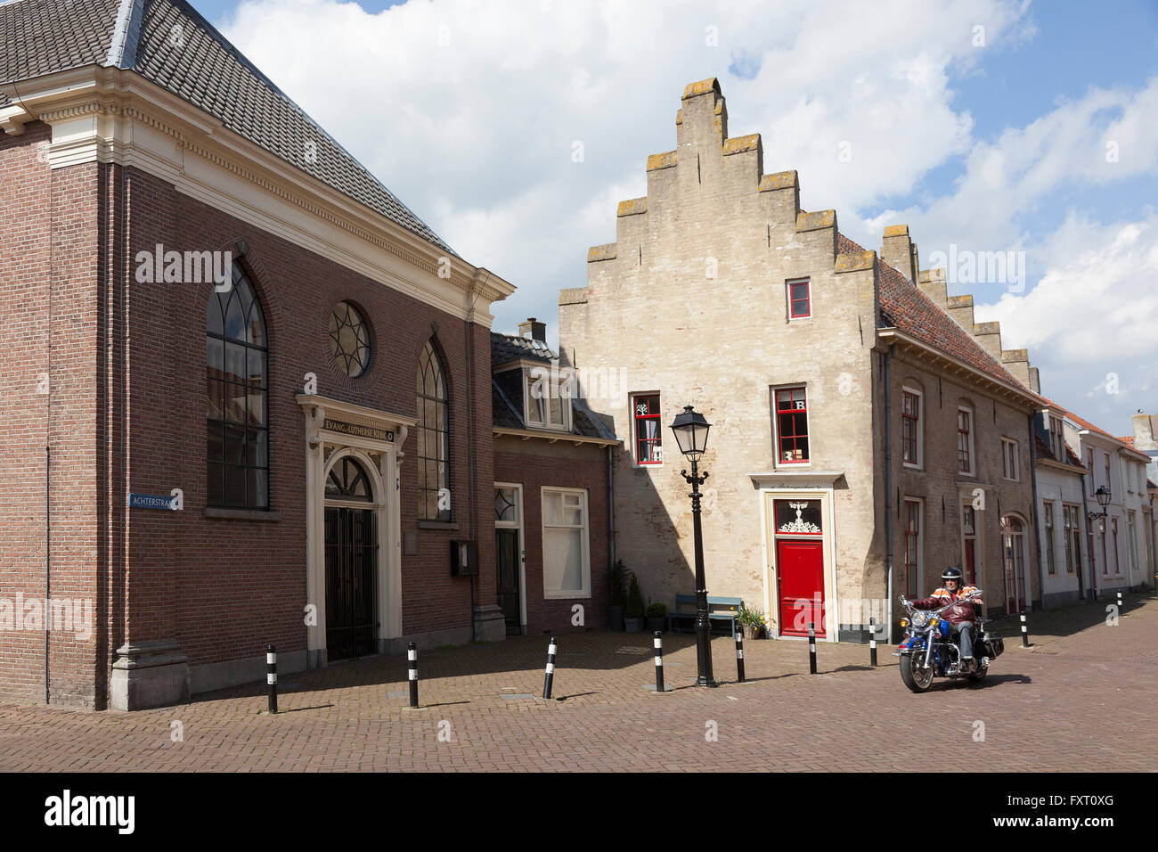 Mann auf dem Motorrad geht Altbauten im mittelalterlichen Zentrum der niederländischen Stadt Culemburg an sonnigen Tag Stockfoto