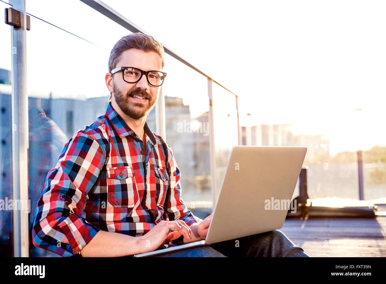 Geschäftsmann, arbeiten von zu Hause am Laptop, am Balkon sitzen Stockfoto