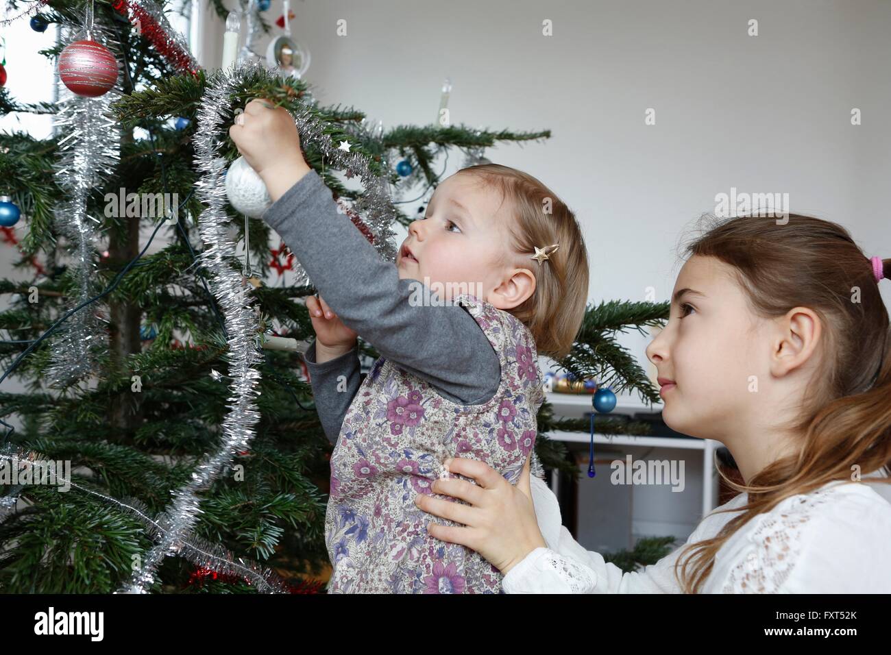 Seitenansicht der großen Schwester helfen Mädchen schmücken Weihnachtsbaum Stockfoto