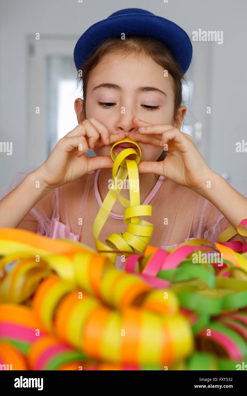 Mädchen mit blauen Hut nach unten bläst Partystromer Stockfoto