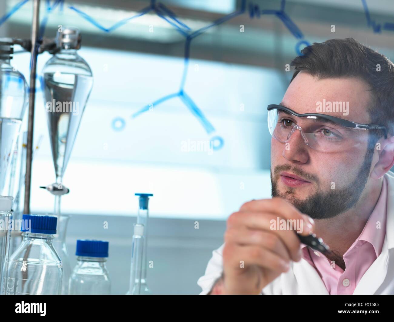 Junge männliche Wissenschaftler Blick auf Antibiotika chemische Formel in pharmazeutischen Forschungslabor Stockfoto