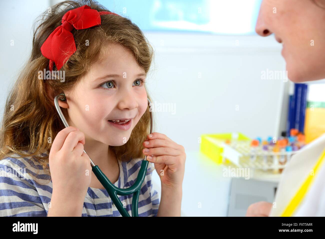 Anhören des Arztes Brust mit Stethoskop lächelnd Mädchen Stockfoto