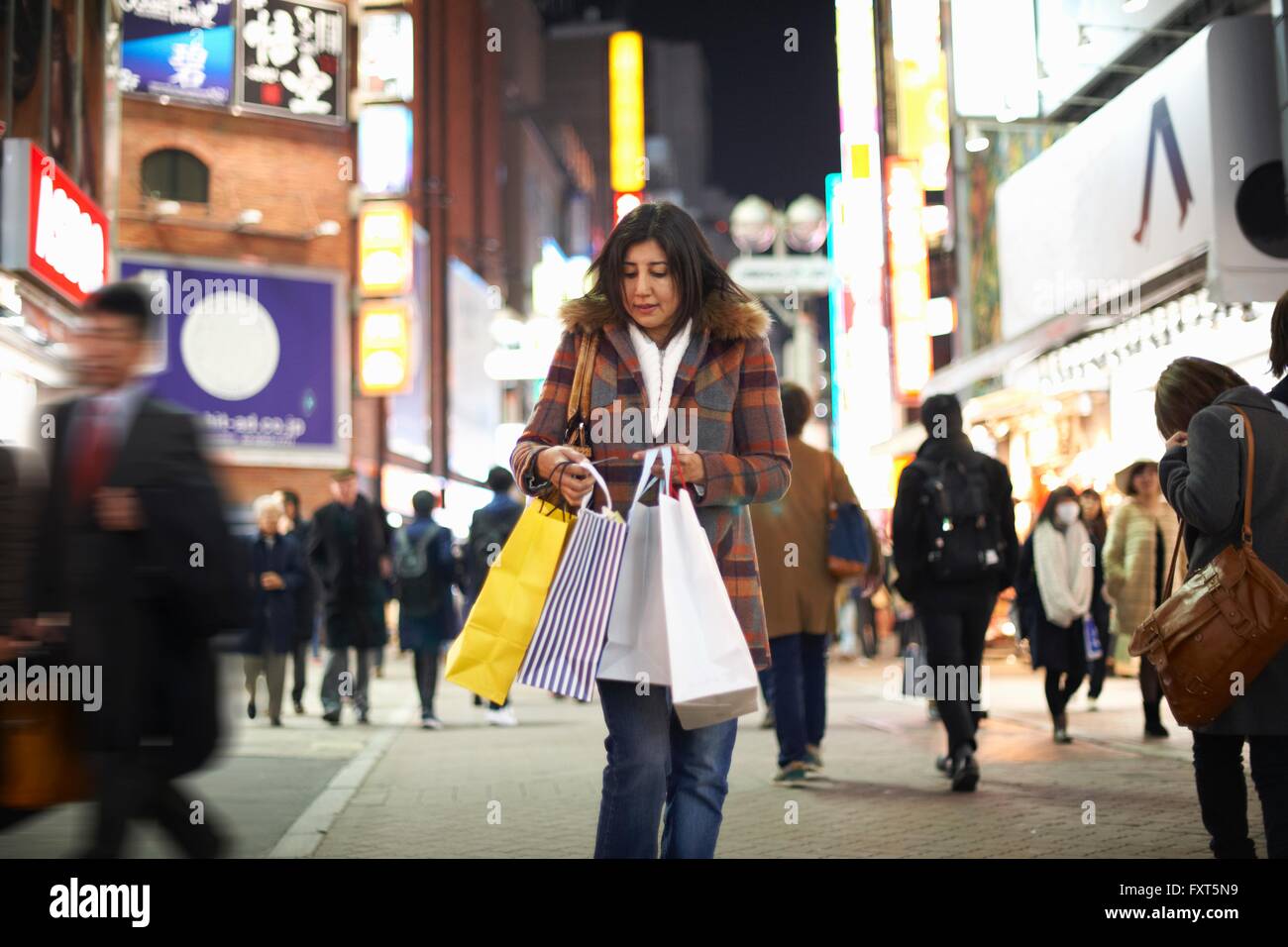 Vorderansicht des Reife Frau Einkaufstaschen in Stadt in der Nacht blickte, Shibuya, Tokyo, Japan Stockfoto