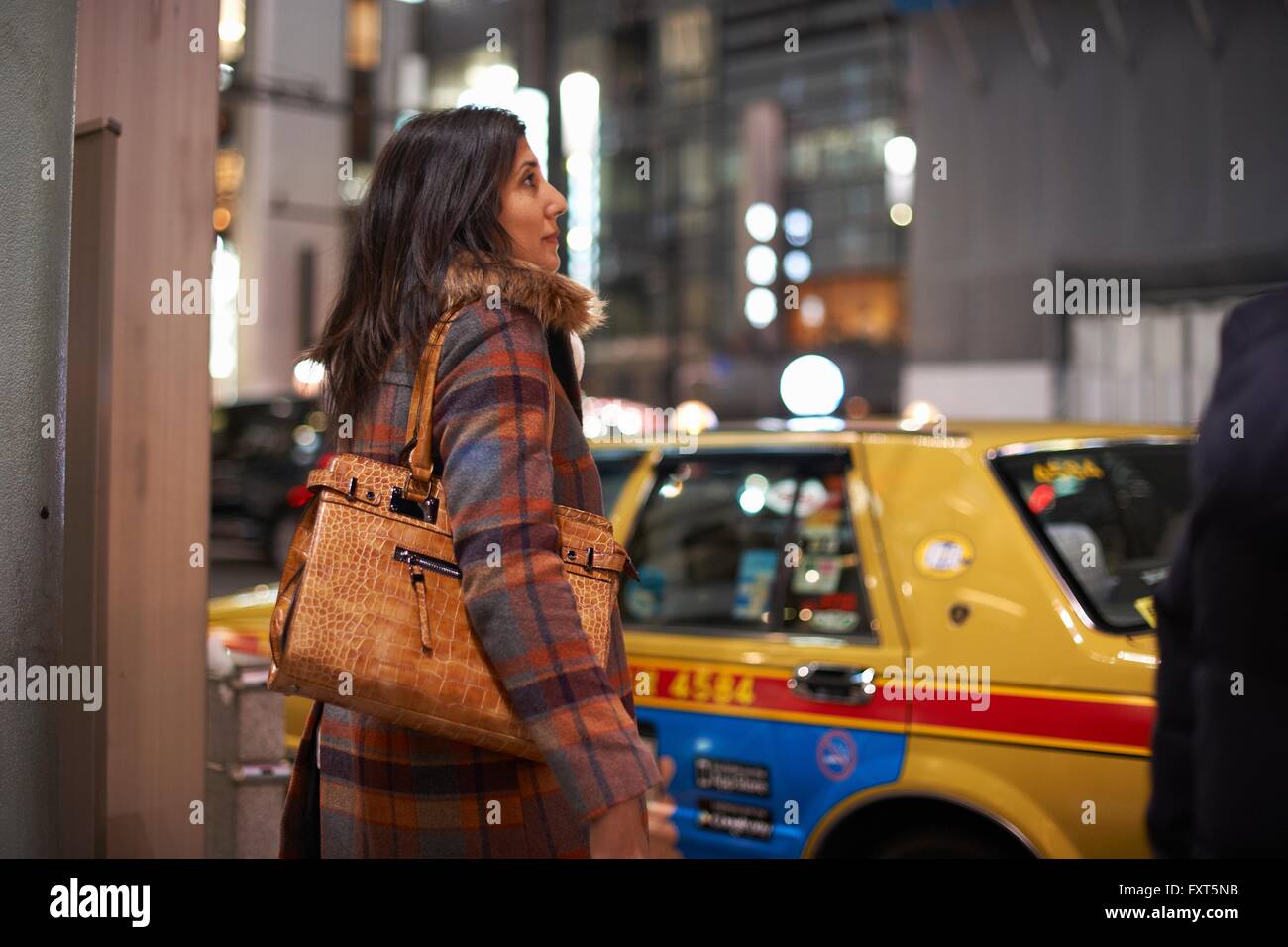 Seitenansicht des Reife Frau tragen Handtasche auf Schulter, die darauf warten, überqueren Straßen, Ginza, Tokio, Japan Stockfoto