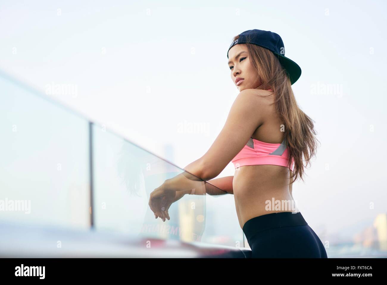 Junge Frau trägt Sportkleidung und Baseball-Cap mit Blick vom Ufer, Hong Kong Stockfoto
