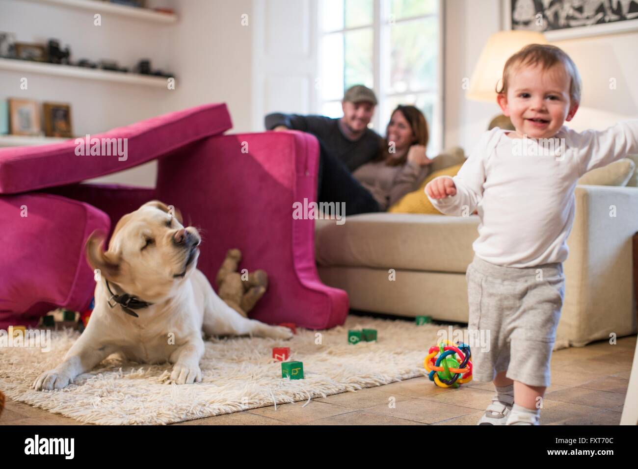 Baby Boy und Haustier Hund spielen im Fort von Sofakissen, Blick auf die Kamera zu Lächeln gemacht Stockfoto