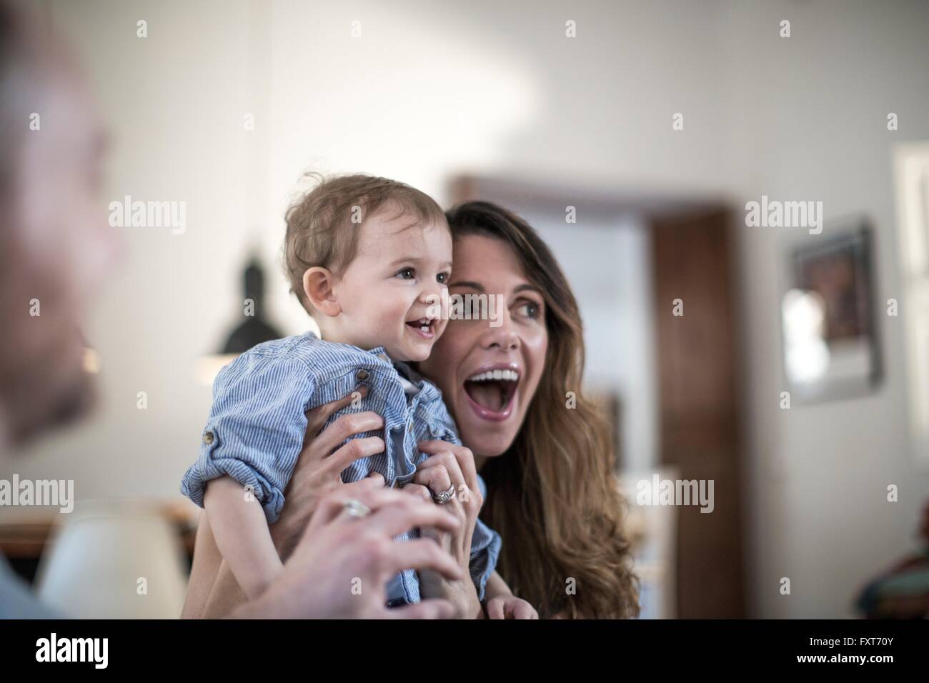 Mutter hält lächelnden jungen, offenen Mund vor Überraschung Stockfoto