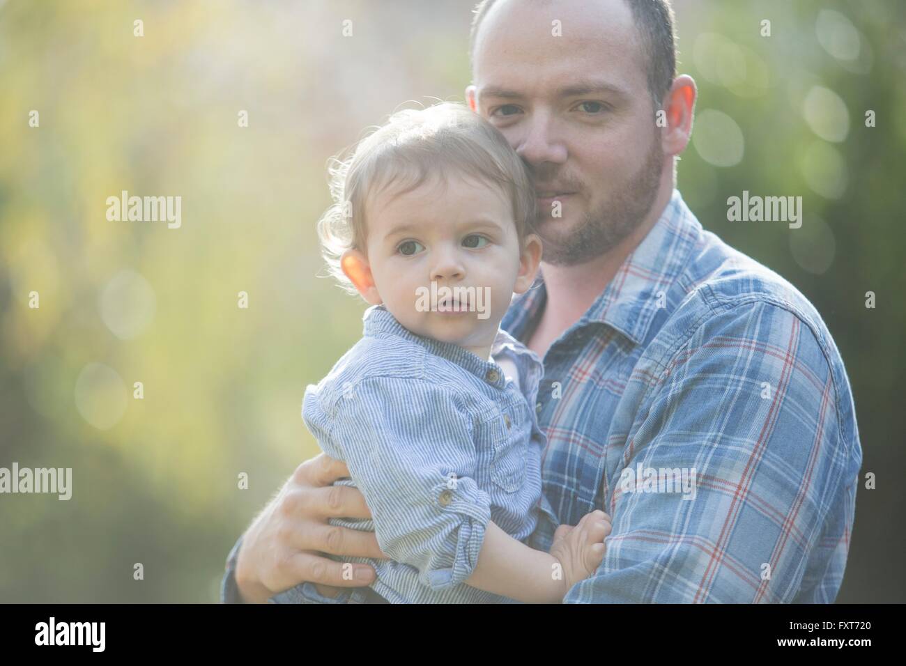 Vater umarmt Baby Boy, Blick in die Kamera Stockfoto