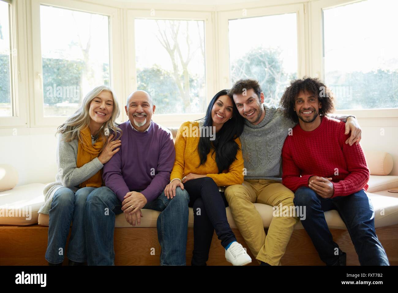 Familie nebeneinander am Fensterplatz mit Blick auf die Kamera zu Lächeln Stockfoto
