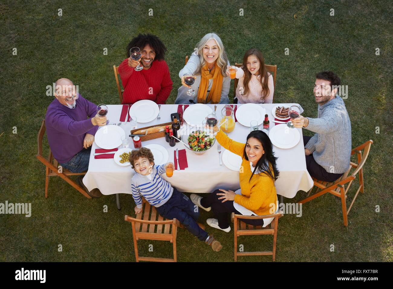 Draufsicht der Multi Familiengeneration Speisen im freien Blick bis in die Kamera, macht ein Toast lächelnd Stockfoto