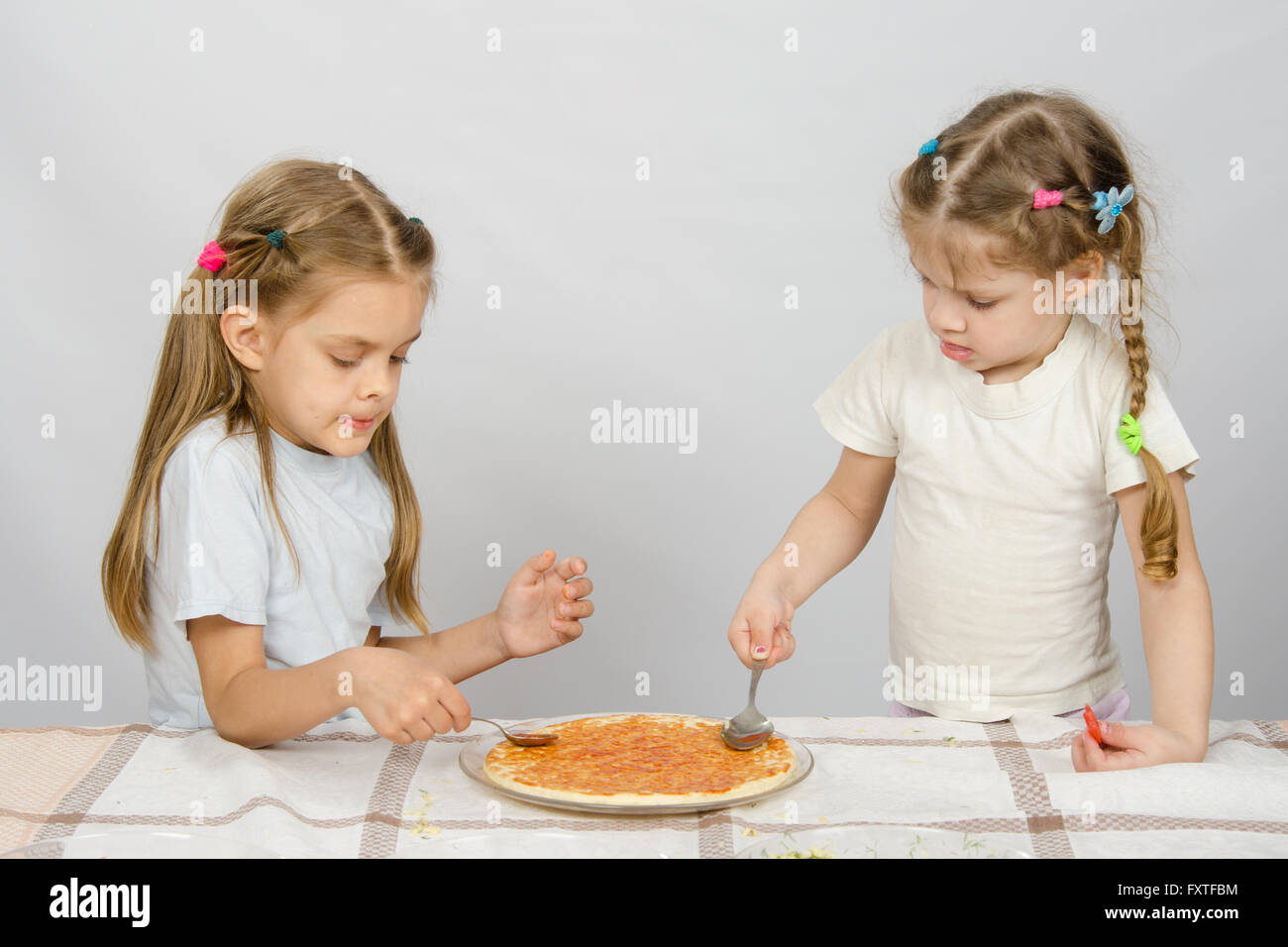 Zwei kleine Schwestern konzentriert Abstrich Sauce Basis pizza Stockfoto