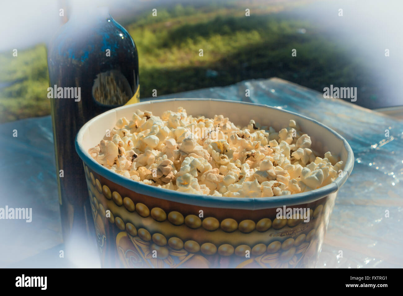 Auf dem Tisch, Popcorn in großen Glas und eine Flasche Wein. Camping. Stockfoto