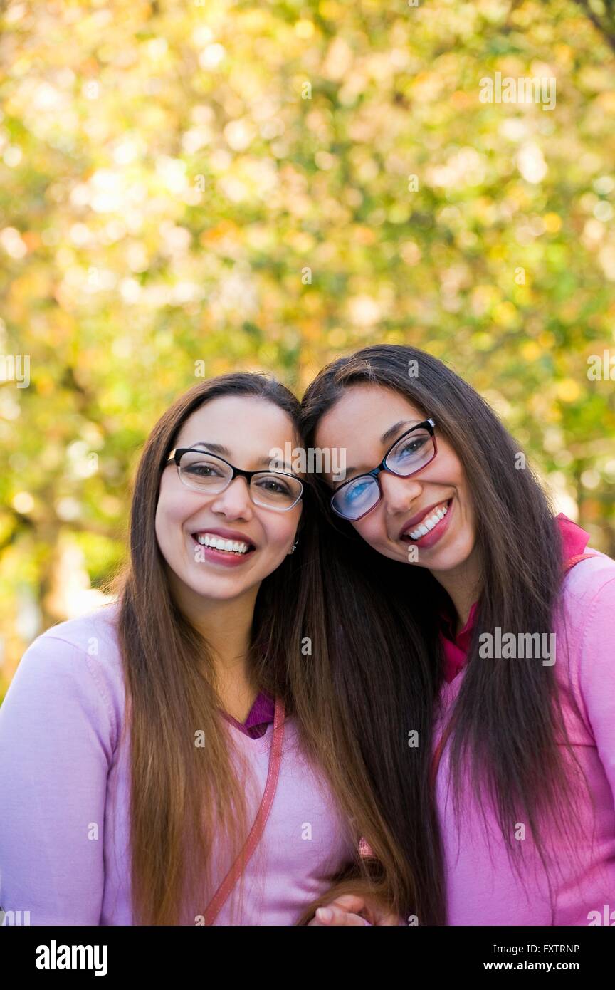 Zwillingsschwestern Lächeln breit im park Stockfoto