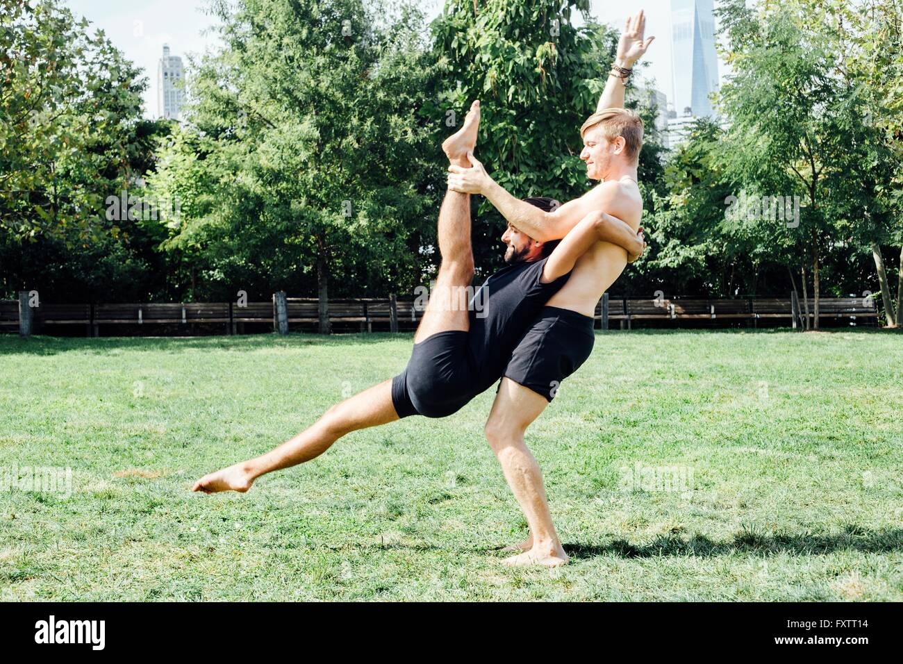 Zwei Männer, die Yoga praktizieren Liftposition im park Stockfoto