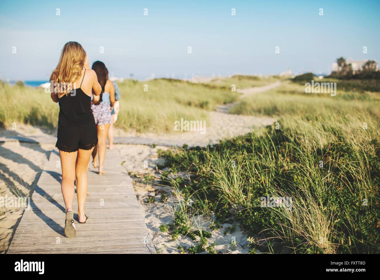 Rückansicht der Frauen am Strand zu Fuß auf Küstenweg Stockfoto