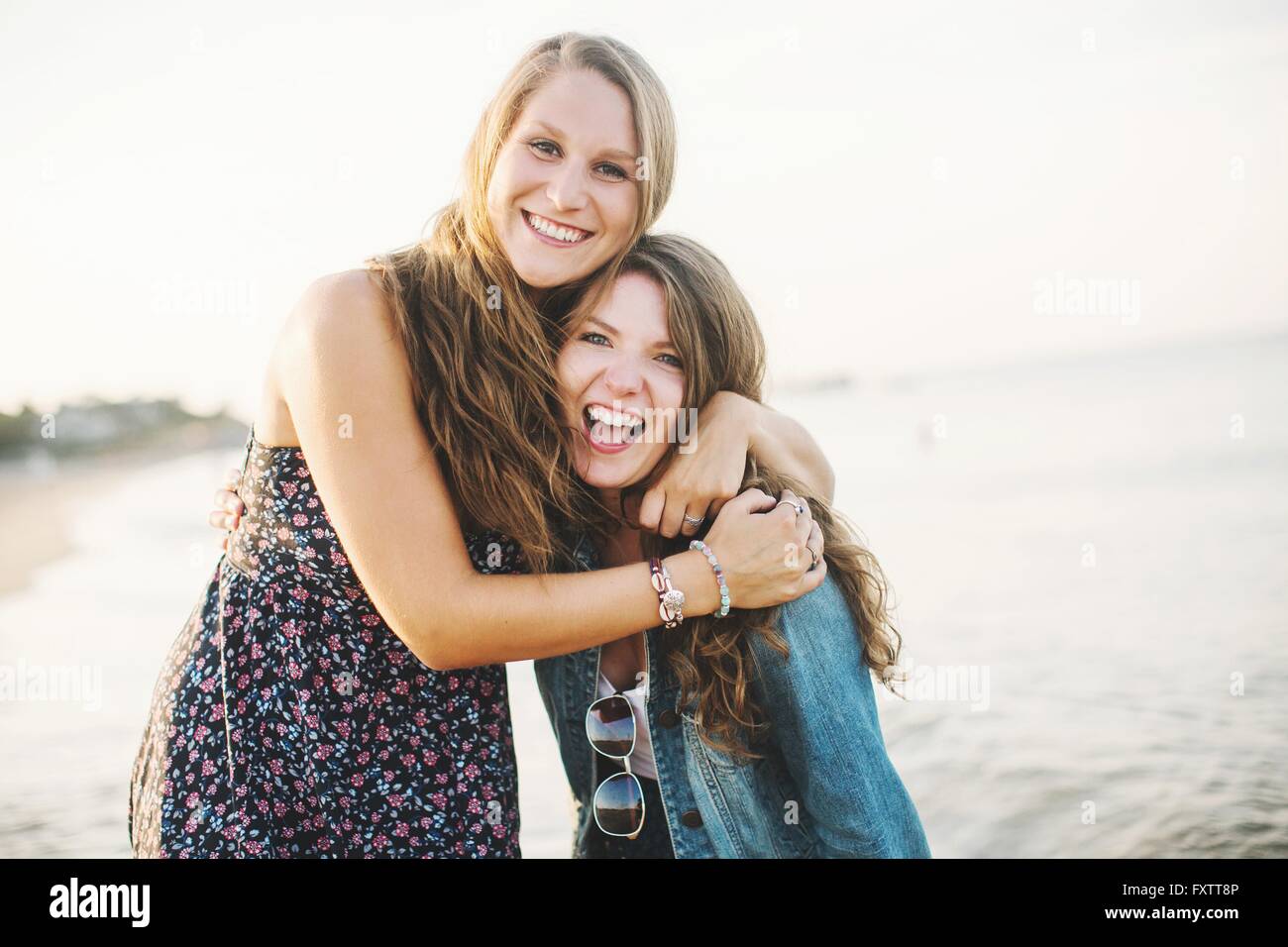 Frauen vor Meer umarmt, Blick in die Kamera Lächeln Stockfoto