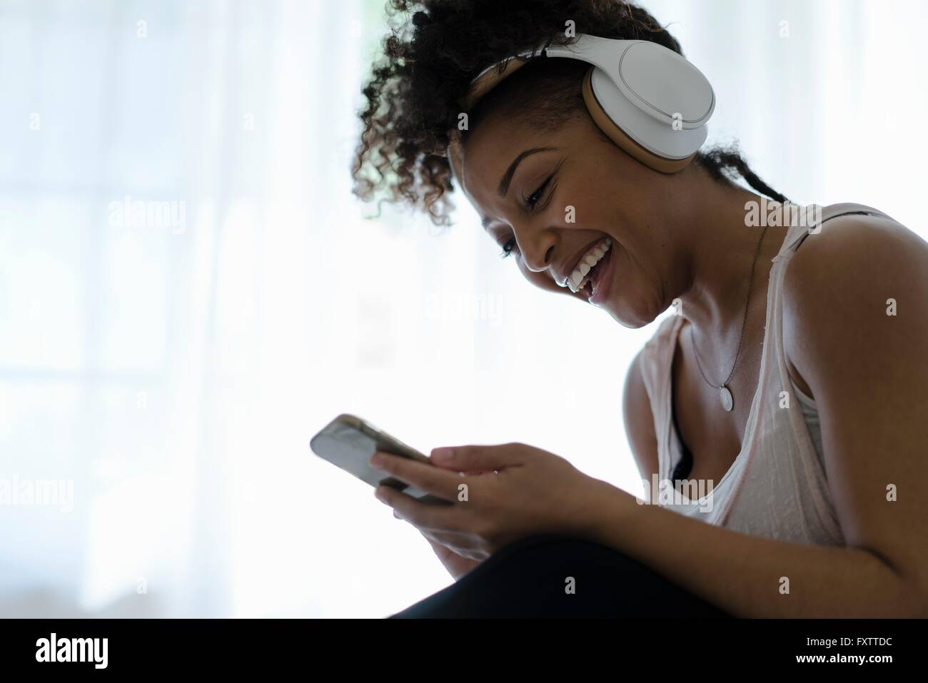 Frau mit Kopfhörern, mit Blick auf Smartphone, lachen Stockfoto