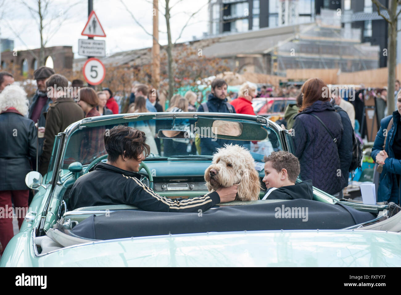 Zwei Kinder sitzen in einem klassischen Auto mit ihrem Hund, posieren für Menschen am Classic Car Boot Sale Cubitt Square, Kings Cross Stockfoto