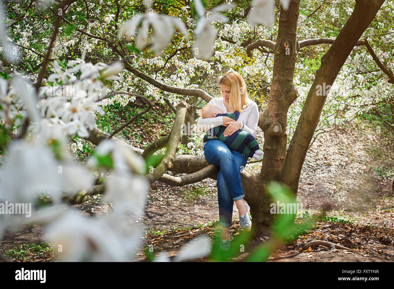 Mama mit Baby sitzend auf Ast im blühenden Frühlingsgarten Stockfoto