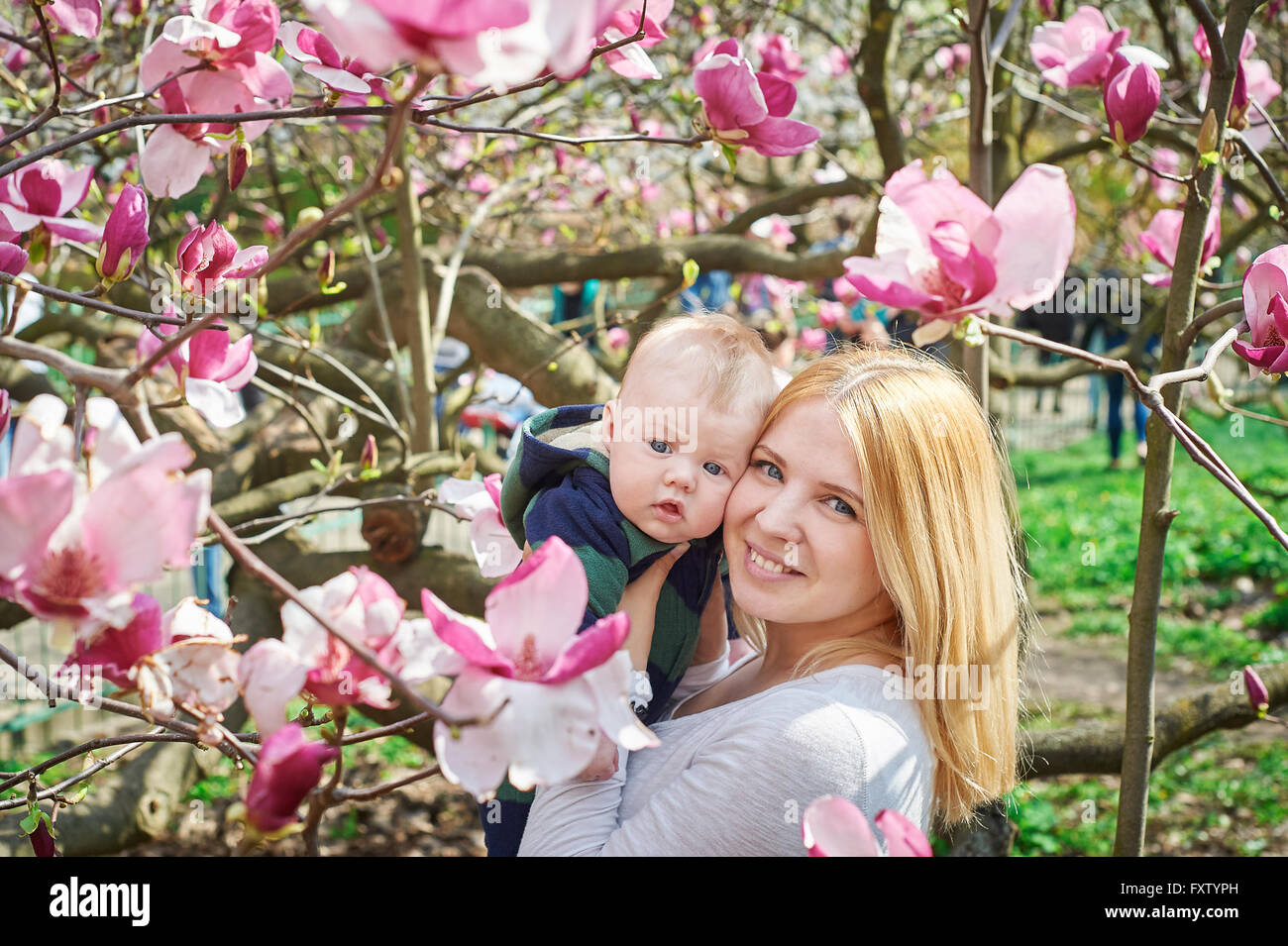 Mutter halten Baby im blühenden Magnolien-Garten Stockfoto
