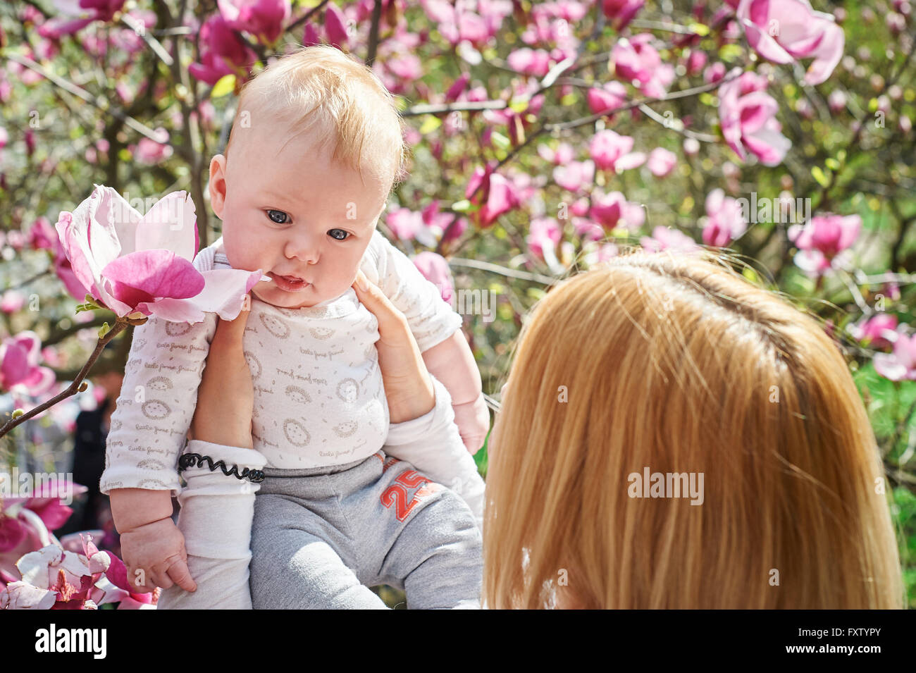 Mutter halten Baby im blühenden Magnolien-Garten Stockfoto
