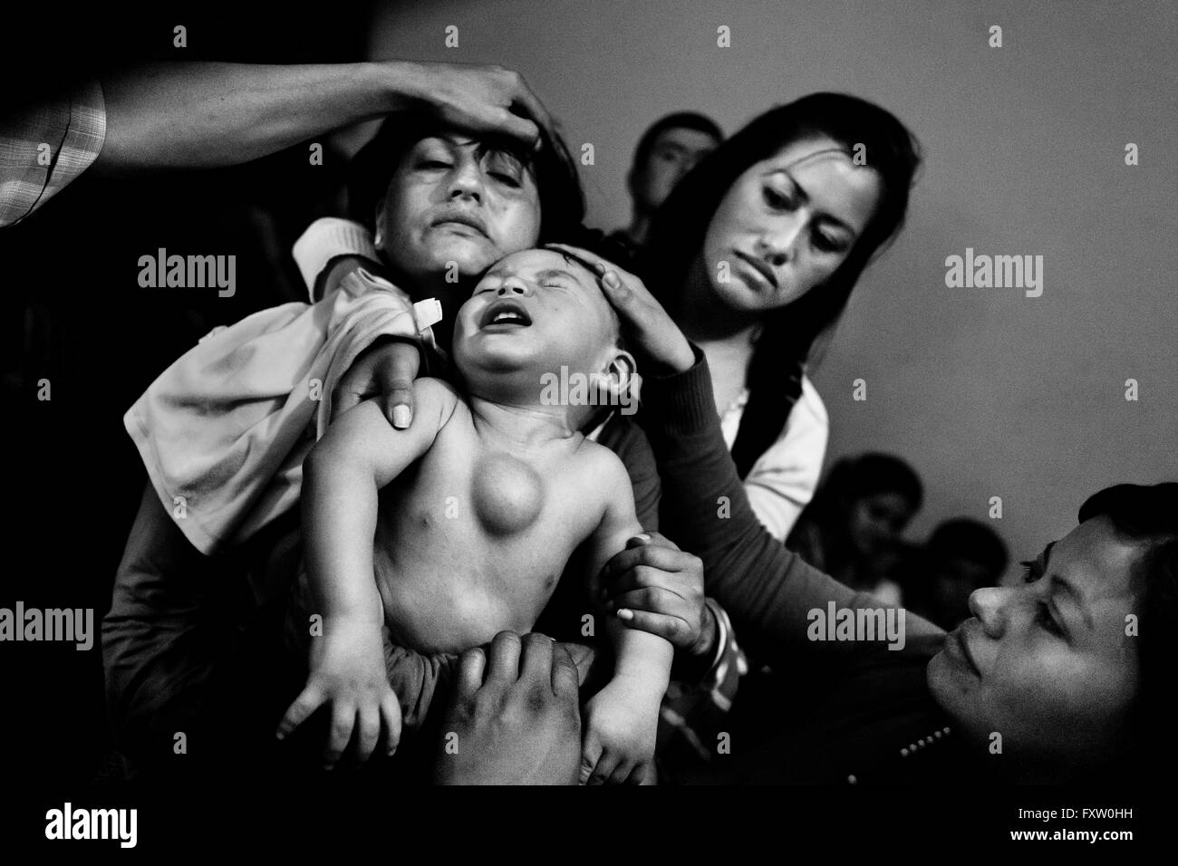 Eine kolumbianische Mutter hält ihr Baby junge, dass einen Tumor in seiner Brust, während des religiösen heilenden Rituals in Bogota, Kolumbien. Stockfoto