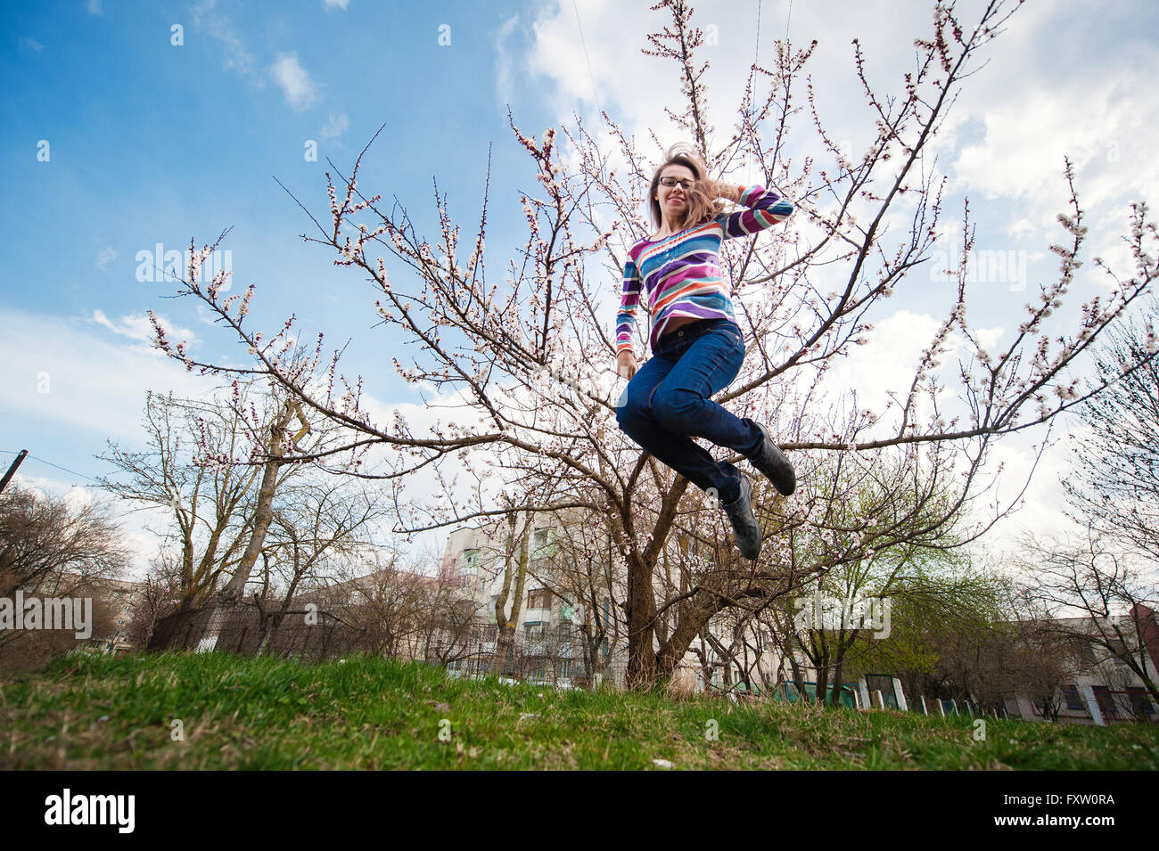 Schöne glückliche Frau, die im Frühling blühenden Garten springen Stockfoto