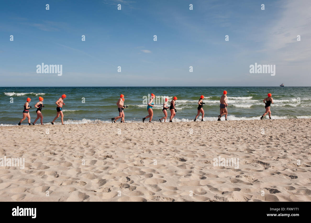 Winter-Schwimmer, die entlang des Strandes in Wladyslawowo Meeresküste, Polen, Europa, Menschen beim aktiven Sport im Meer Aufwärmen Stockfoto