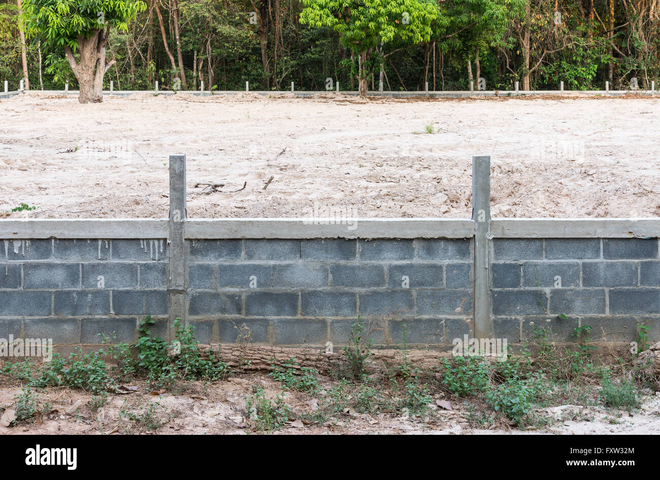 Betonwand mit Sandboden für Urbarmachung in der Nähe von der Grenze des Waldes. Stockfoto