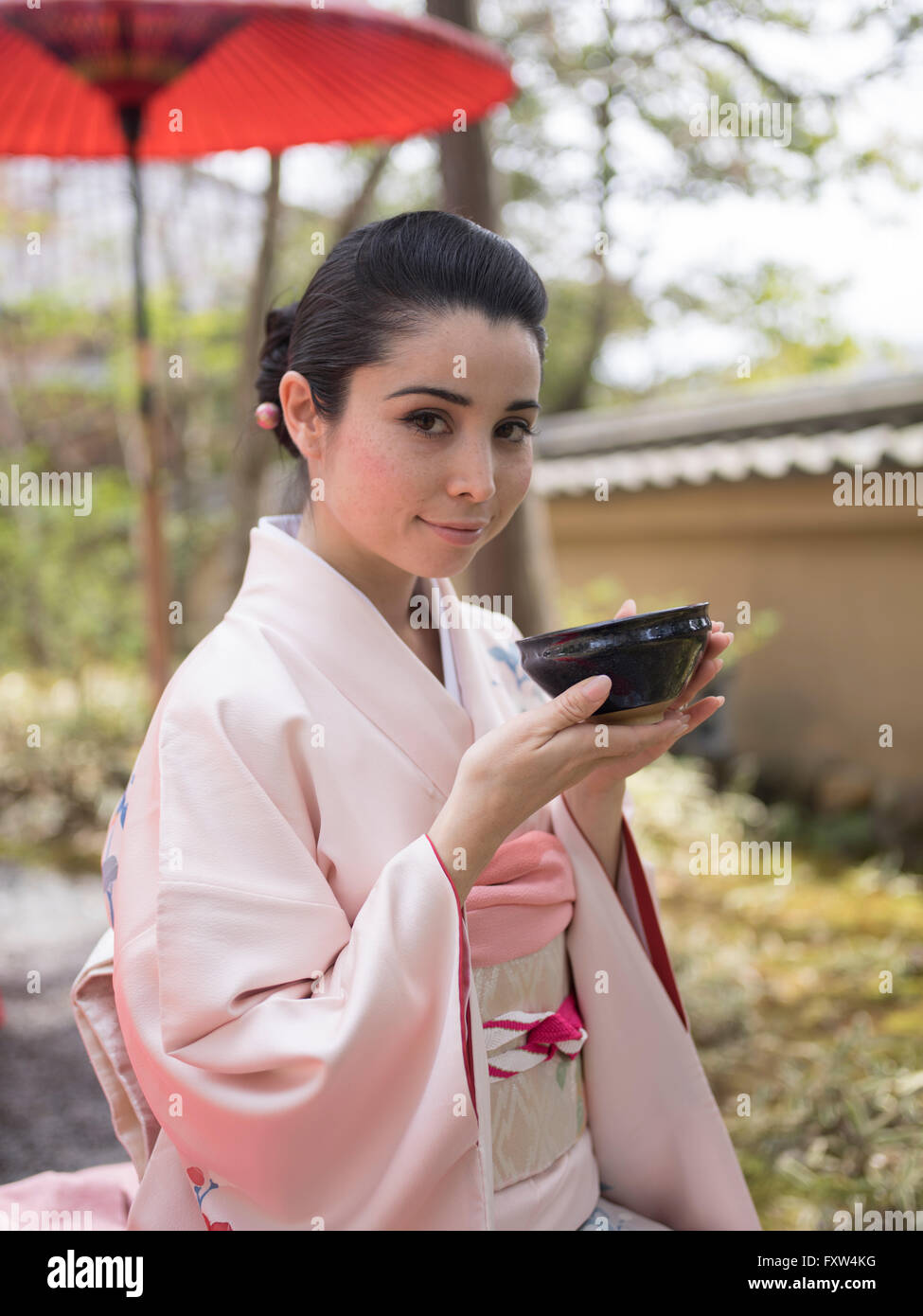 Japanische Frau im Kimono eine Schale mit grünem Tee zu trinken, in den Gärten des Kinkaku-Ji, ein Zen-buddhistischen Tempel in Kyoto, Japan. Stockfoto