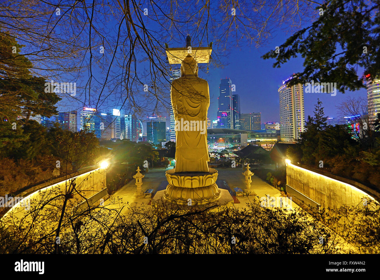 Buddha-Statue und die Skyline der Stadt am Bongeunsa-Tempel bei Sonnenuntergang in Seoul, Korea Stockfoto