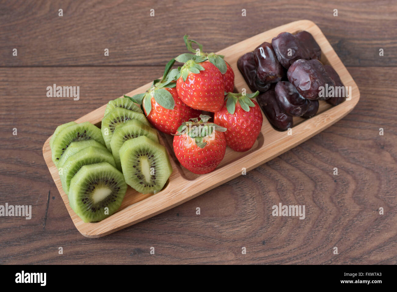 Erdbeeren, Kiwi und Termine in einem Bambus-Plateau. Frisches Obst und getrocknete Früchte Platte. Salat von Früchten. Stockfoto