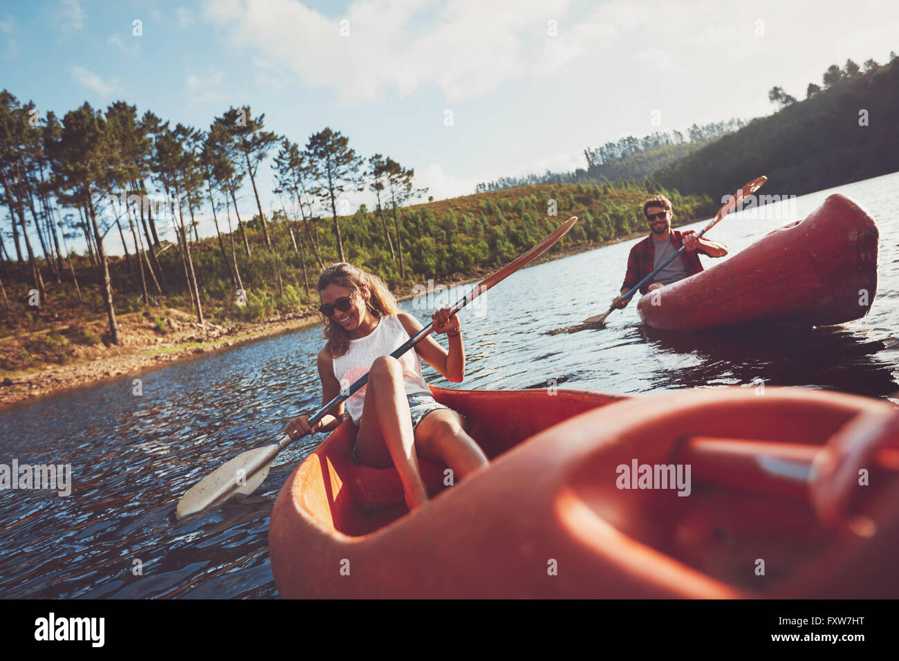 Glückliches junges Paar Kanufahren auf See zusammen. Mann und Frau Kajak an einem Sommertag. Stockfoto