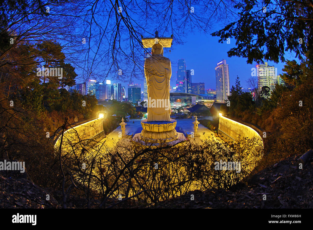 Buddha-Statue und die Skyline der Stadt am Bongeunsa-Tempel bei Sonnenuntergang in Seoul, Korea Stockfoto