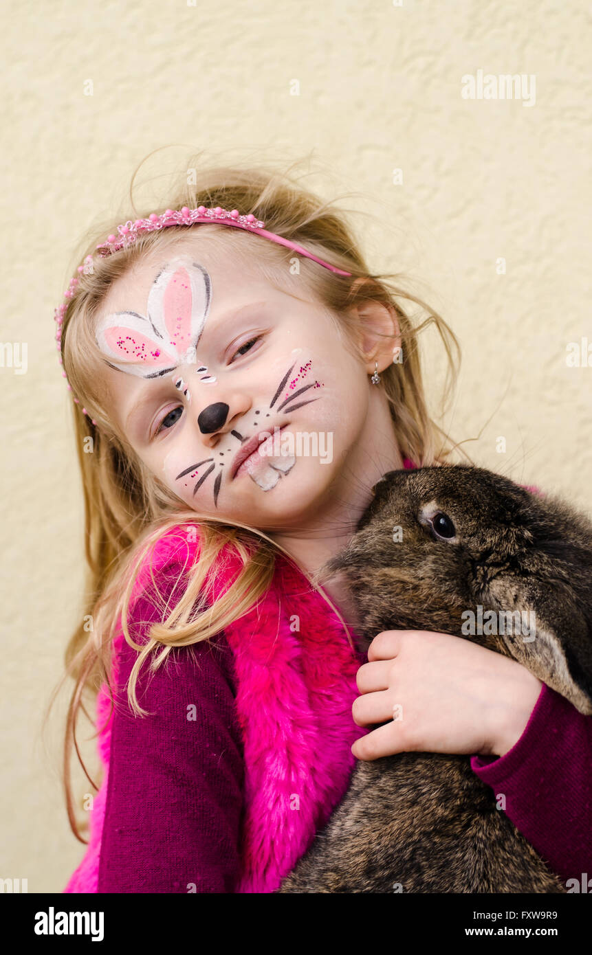 lächelnd schönes Kind mit Face-Painting von Hasen und Kaninchen Tier in Händen Stockfoto