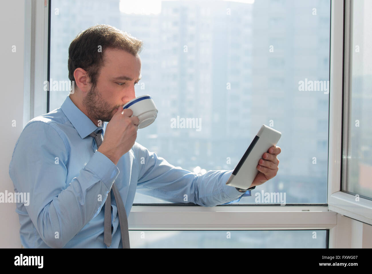 Geschäftsmann, trinken Kaffee und Blick auf digitale Tablet-Gerät Stockfoto