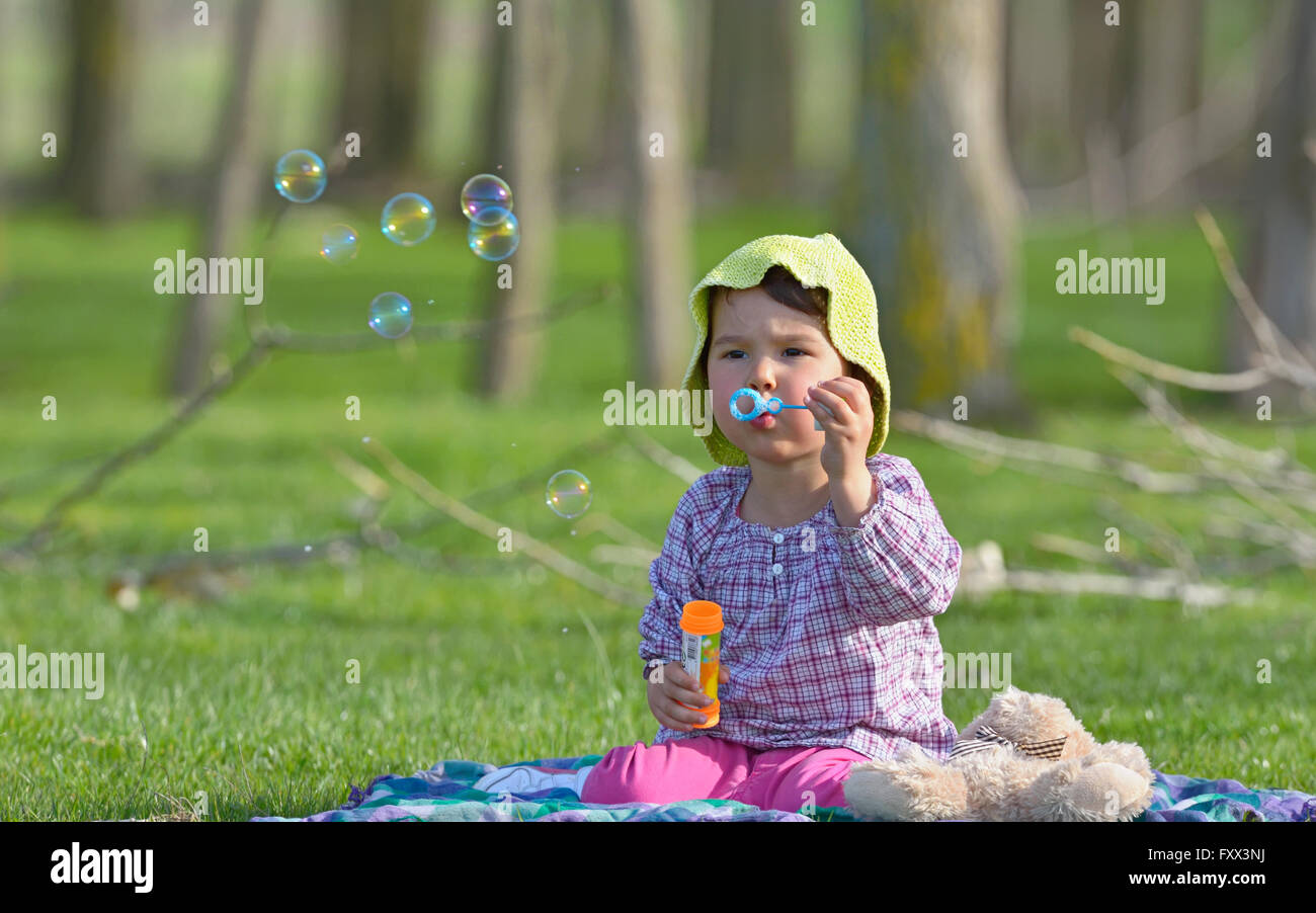 kleines Mädchen bläst ein Seifenblasen im Wald Stockfoto