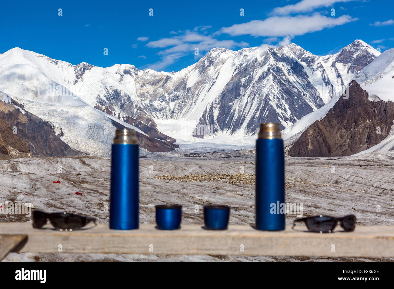 Zwei blaue Reise Thermoskannen Tassen und Sonnenbrille auf Holztisch und Berglandschaft Stockfoto
